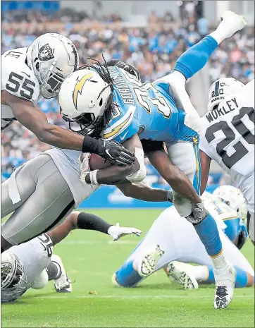  ?? HARRY HOW — GETTY IMAGES ?? The Chargers’ Melvin Gordon is hit short of the goal line by the Raiders’ Marquel Lee and Marcus Gilchrist in Sunday’s game.