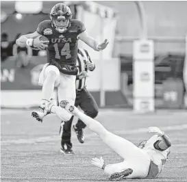  ?? Andres Leighton / Associated Press ?? UTSA quarterbac­k Dalton Sturm leaps over New Mexico safety Ryan Santos to pick up extra yardage in the second half of Saturday’s New Mexico Bowl.