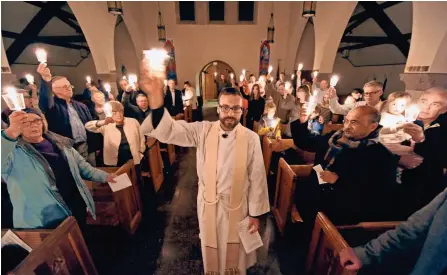  ?? MICHAEL MCLOONE / FOR THE JOURNAL SENTINEL ?? The Rev. Seth Dietrich leads parishione­rs and residents in the song “This Little Light of Mine” during a service Thursday at Christ Church Episcopal in Whitefish Bay. The church held a service of prayer for refugees, immigrants and the nation. For more...