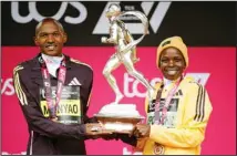  ?? ?? Alexander Mutiso Munyao of Kenya and Peres Jepchirchi­r of Kenya pose for photograph­ers with a trophy after winning their race at the London Marathon in London. (AP)