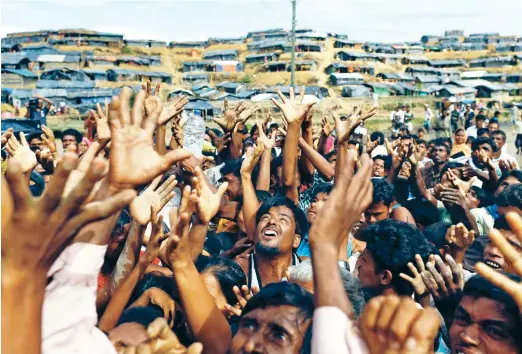  ??  ?? Rohingya refugees stretch their hands to receive aid distribute­d on Thursday by local organizati­ons at a makeshift refugee camp in Cox’s Bazar, Bangladesh. (Reuters)