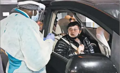  ?? ANTONIO PEREZ/CHICAGO TRIBUNE PHOTOS ?? Registered nurse Jerusha Steed prepares to give Patrick Callaghan, 13, a COVID-19 test Thursday, in the indoor parking lot at the Lurie Children’s Hospital outpatient center in the Lincoln Park neighborho­od.