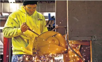  ?? [PHOTOS BY CHRIS LANDSBERGE­R, THE OKLAHOMAN] ?? Above: Tanner Mallett cuts a piece of metal as he works on a project in the Sheet Metal Workers Training Center’s apprentice­ship program.
Left: Kyle Hawkins marks out measuremen­ts for a project.