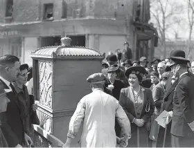  ?? Davis/Getty Images ?? On May 2, King George VI and Queen Elizabeth visited the city and are here being shown a sedan chair rescued from the ruins of a bombed building