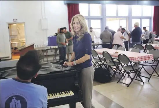  ?? Photograph­s by Dania Maxwell Los Angeles Times ?? AMIE QUIGLEY listens to Robert Carpenter play piano during a mental health clinic. “We have to look at who should be eligible for housing in Los Angeles,” she said.