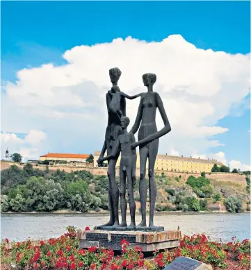  ?? ?? i Living in the moment: the Petrovarad­in Fortress looks down on a war memorial by the Danube, but Novi Sad locals refuse to be victims