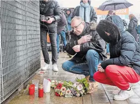  ?? GEORG WENDT DPA VIA THE ASSOCIATED PRESS ?? People place floral tributes on Friday outside the Jehovah's Witness hall where a gunman shot and killed several people in Hamburg, Germany, the night before.