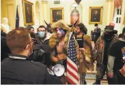  ?? Erin Schaff / New York Times ?? Jacob Anthony Chansley ( center in horned hat) confronts officers Wednesday at the U. S. Capitol.