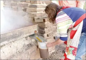  ??  ?? Wanda Biggs of Cane Hill captures sorghum molasses during the 2018 Cane Hill Harvest Festival that will be poured into glass jars and sold to visitors.