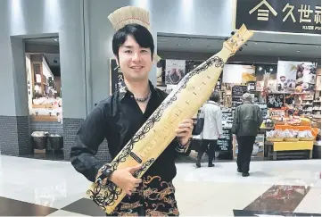  ??  ?? Hikaru with his treasured sape after a performanc­e in a shopping mall in Tokyo, Japan. — Bernama photo