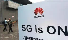  ?? AP FILE PHOTO ?? Visitors walk past a sign advertisin­g 5G services near the Huawei pavilion at the Mobile World Congress in Shanghai in June.