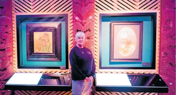  ?? Photo / Milly Fullick ?? Di Michels stands alongside paintings by Charles Goldie and her great-grandfathe­r Thomas Ryan.