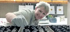  ?? MICHELLE ALLENBERG/POSTMEDIA NETWORK ?? Mary-Beth Benner, owner of Marshville Chocolates in Wainfleet, places chocolates in a display to prepare for the busy days leading up to Easter.