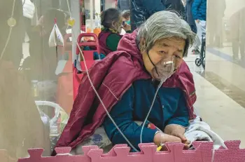  ?? ANDY WONG/AP ?? A coronaviru­s patient on a ventilator receives an IV drip in the hallway of a hospital’s emergency ward in January in Beijing. China’s sudden reopening after two years of a strict “zero-COVID” policy left older people vulnerable.