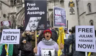  ?? ?? Demonstrat­ors hold banners outside the Royal Courts of Justice in London, Tuesday, 20 February, 2024.