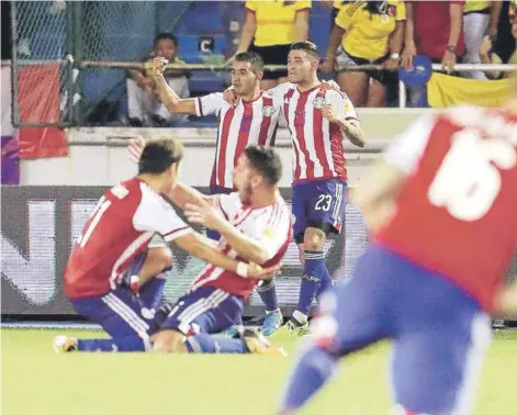  ??  ?? ► Los futbolista­s paraguayos festejan enloquecid­os sobre el césped el definitivo 1-2 de Sanabria.