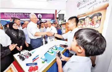  ??  ?? Prime Minister Datuk Seri Najib Tun Razak shaking hands with pupils of Labuan Internatio­nal School who designed the replica Labuan bridge after launching the blueprint at Labuan Square. - Bernama photo