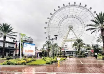  ?? PAUL BRINKMANN/STAFF ?? The Coca-Cola Orlando Eye looms among Hurricane Irma's gray clouds, while a bright red sign says “Closed" and “Be Safe.”