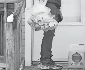  ?? BARBARA J. PERENIC PHOTOS/COLUMBUS DISPATCH ?? Volunteer Liz Alcalde of Clintonvil­le leaves a supply of canned cat food and kitty litter on a South Side home’s front porch as part of the Senior Petcare program.