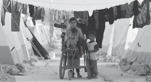  ?? AAREF WATAD / AFP / GETTY IMAGES ?? Displaced Syrian children push a boy on a makeshift wheelchair at a displaced people camp in Idlib province, which is being targeted by Syrian forces, at top.