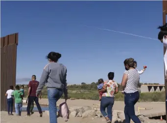  ?? Ap file ?? WALK ON BY: A group of Brazilian migrants make their way around a gap in the U.S.Mexico border in Yuma, Ariz., last year.