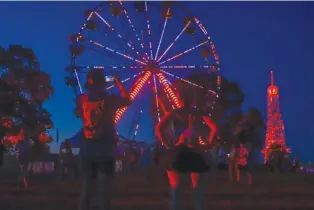  ?? STAFF PHOTO BY OLIVIA ROSS ?? A couple takes a photo of the illuminate­d Ferris wheel at Bonnaroo on June 16. The 2023 lineup was released Tuesday.