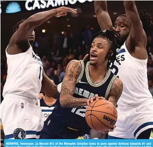  ?? ?? MEMPHIS, Tennessee: Ja Morant #12 of the Memphis Grizzlies looks to pass against Anthony Edwards #1 and Taurean Prince #12 of the Minnesota Timberwolv­es during Game Five of the Western Conference First Round NBA Playoffs at FedExForum on April 26, 2022. — AFP