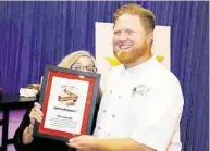  ?? Jeremy Carter / Houston Chronicle ?? Houston Chronicle restaurant critic Alison Cook gets behind her Top 100 Houston Restaurant­s award that was presented to Haven chef/owner Randy Evans.