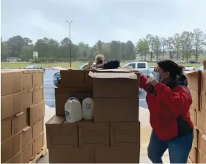  ?? (Special to The Commercial) ?? Jamie Storey (front) and Michele Jones, both White Hall Family Church members, distribute fresh produce from the U.S. Department of Agricultur­e’s Farmers to Families Food Box Program.