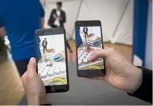  ??  ?? An exhibitor demonstrat­es a multiplaye­r AR game that can be played between both iPhone and Android smartphone­s.