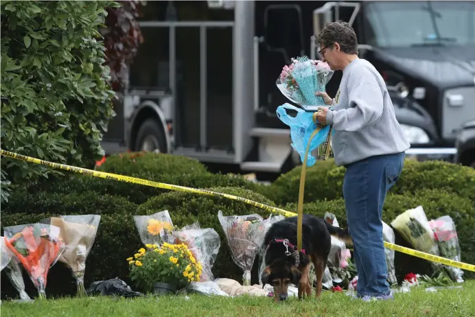  ?? (Reuters) ?? A WOMAN brings flowers to an impromptu memorial at the Tree of Life Synagogue following the previous day’s shooting at the synagogue in Pittsburgh, on October 28.