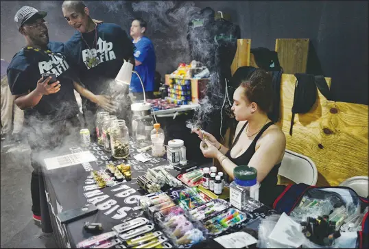  ?? RICHARD VOGEL / ASSOCIATED PRESS FILE (2019) ?? A cannabis and parapherna­lia vendor smokes a marijuana cigarette April 15,2019, as she waits for customers at Rev-up, a cannabis marketplac­e in Los Angeles.