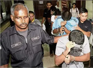  ??  ?? Facing
charges: The four teenagers being escorted by the police to the George Town Court.