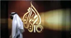  ?? — AP ?? DOHA: In this file photo, a Qatari employee of Al Jazeera Arabic language TV news channel walks past the logo of Al Jazeera.