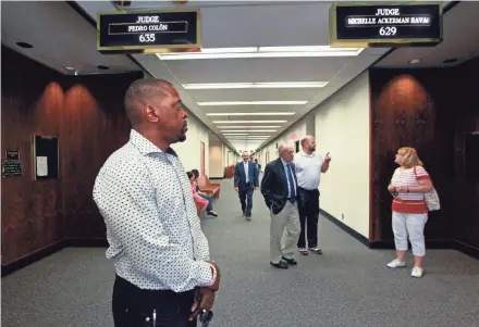  ?? ANGELA PETERSON / MILWAUKEE JOURNAL SENTINEL ?? Curtis Fisher, left, waits for Judge Michelle Havas’ courtroom to open July 3. Havas, at right standing under her sign, answers questions before going into court.