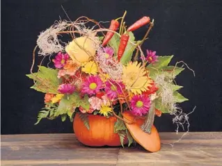  ?? RITTNERS FLORAL SCHOOL ?? For a festive fall centerpiec­e, try hollowing out a pumpkin. Drop in a plastic liner or a glass vase filled with floral foam. Fill the foam with seasonal flowers, branch material, Spanish moss and dried peppers or pepper berries. Prop the pumpkin top against the arrangemen­t as a finishing touch.