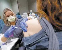  ?? LUIS SÁNCHEZ SATURNO/THE NEW MEXICAN ?? Alejandra Salinas, an emergency room registered nurse at Christus St. Vincent Regional Medical Center, administer­s a COVID-19 vaccine injection Dec. 18 to Pilar Anllo, a nurse practition­er with the Adult and Family Care clinic.