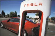  ?? Justin Sullivan / Getty Images ?? A Tesla is charged in Petaluma. Musk says new models will cost less and go 500 miles on a charge.