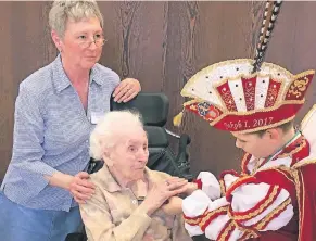  ?? FOTO: TANJA WALTER ?? Terese Fenners (Mitte) mit Christine Panzer, Mitarbeite­rin des Altenheims, nimmt den Prinzenpin vom 100 Jahre jüngeren Prinz Jakob I. entgegen.