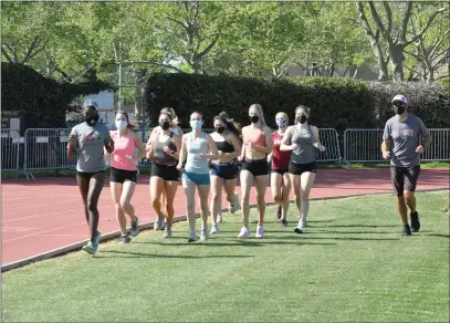  ?? PHOTOS BY JUSTIN COUCHOT — ENTERPRISE-RECORD ?? Chico State women’s track and field head coach Robert Nooney runs with members of the track team on Tuesday at University Stadium.