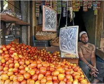  ?? WASHINGTON POST/BLOOMBERG ?? An Indian tomato vendor displays his wares at a market in Bangalore. Bad weather and flooding have seen tomato prices rise dramatical­ly, putting the kitchen staple beyond the reach of many poorer families.