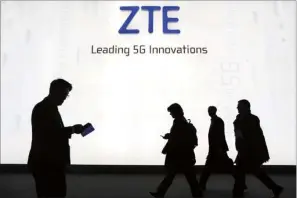  ?? SIMON DAWSON / BLOOMBERG ?? Attendees pass by the ZTE stand during the Mobile World Congress in Barcelona, Spain. ZTE and Huawei, with their cutting-edge technologi­es and massive market share, are playing a leading role in the internatio­nal 5G standards-setting body 3GPP.