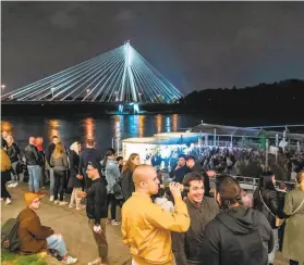  ?? Wojtek Radwanski / AFP / Getty Images ?? People gather early Saturday along the Vistula River in Warsaw to celebrate the easing of virus restrictio­ns that had been in place for months in Poland.