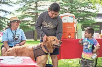  ?? DORGAN/JACKSON HOLE NEWS & GUIDE VIA AP RYAN ?? Eduardo Gomez Hernandez, 12, and Gabriel Gomez, 3, meet Pet Partners volunteer Amanda Soliday’s golden retriever, Otis, during a Teton County Pet Partners event in Jackson, Wyo. The organizati­on currently has 36 active teams of handlers and therapy dogs and routinely partners with a number of local organizati­ons.