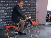  ??  ?? Le président de la Métropole David Kimelfeld sur le nouveau Vélo’v entièremen­t revu. Une batterie amovible permet de le transforme­r en hybride électrique.