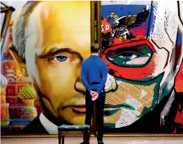  ?? — AFP ?? A man looks at a painting depicting Russian President Vladimir Putin at the ‘ Superputin’ exhibition at UMAM museum in Moscow on Wednesday.