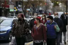  ?? AP PHOTO/BURHAN OZBILICI ?? People wearing masks to help protect against the spread of coronaviru­s, walk, in Ankara, Turkey, Monday.