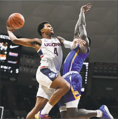  ?? Jessica Hill / Associated Press ?? UConn’s Jalen Adams, left, drives to the basket as Morehead State’s Jordan Walker defends during the first half of Thursday’s game in Storrs.