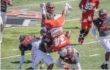  ?? ROBERTO E. ROSALES/JOURNAL ?? University of New Mexico running back Bobby Cole gets flipped by UNM defenders Reco Hannah (23) and Devin Sanders (19) Saturday at University Stadium during the Lobos’ spring practice finale.