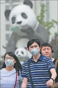  ?? WANG ZHUANGFEI AND FENG YONGBIN / CHINA DAILY ?? Left: Many people in the Wangjing area of Beijing don masks on Thursday, following health officials’ recommenda­tions. Right: A visitor takes a photo of the Forbidden City through the haze of a sandstorm.